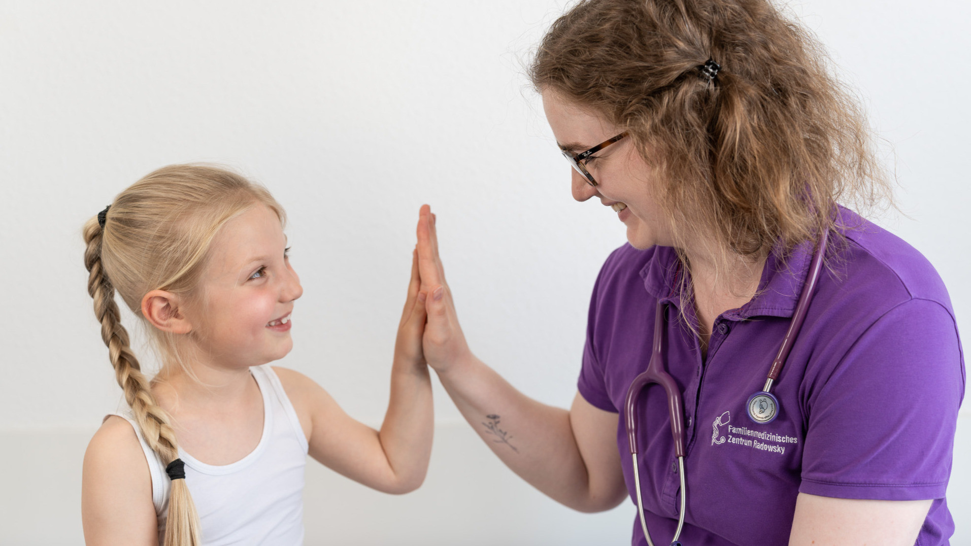 nebeneinander sitzend, Handfläche eines kleinen Mädchens berührt Handfläche Ärztin
